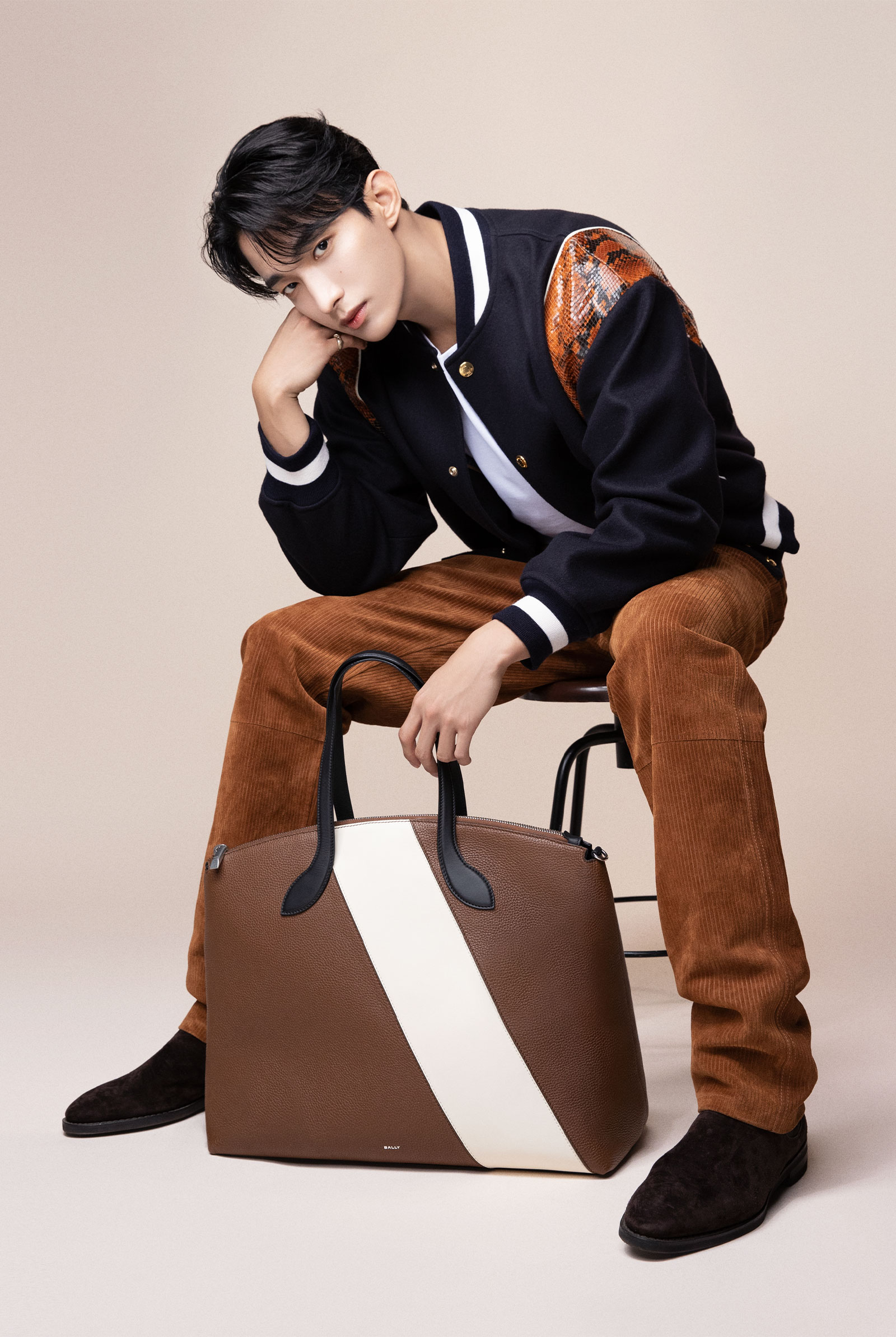 Bally released DK's new images donning brown corduroy pants and a varsity jacket adorned with a reptile-patterned trim