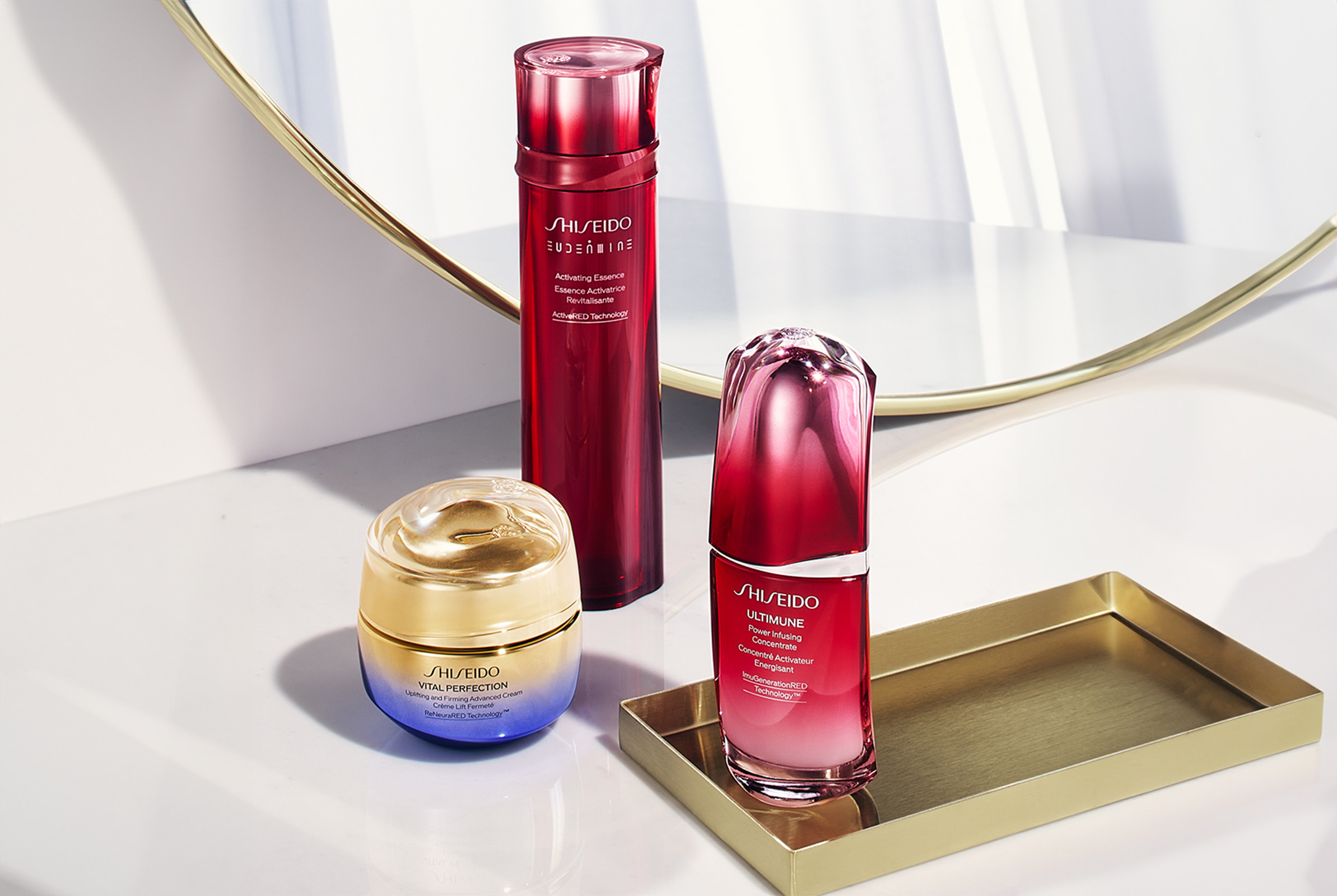 The Shiseido VITAL PERFECTION treatment with the Eudermine Activating Essence and ULTIMUNE Power Infusing Concentrate in a red bottle, while VITAL PERFECTION Uplifting and Firming Advanced Cream in a gradient violet to gold jar.