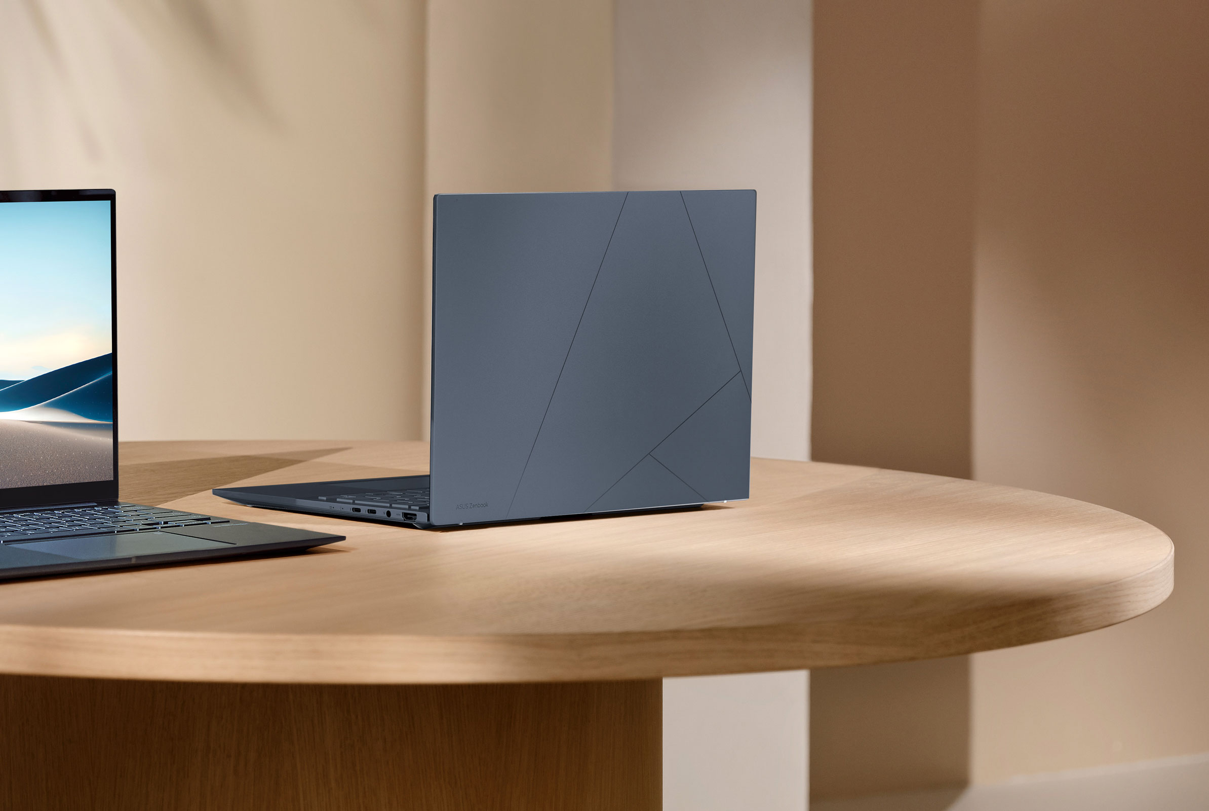 Two ASUS Zenbook 14 OLED laptops on a wooden table